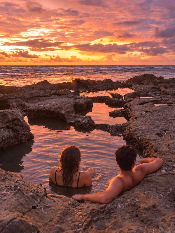 Couple relaxing in a Mal País tide pool at sunset, Costa Rica